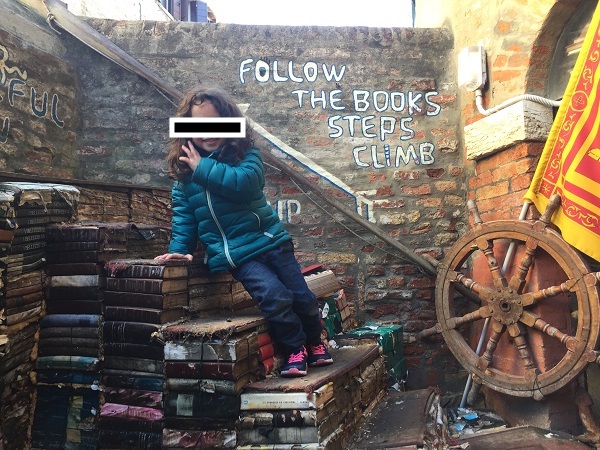 LIbreria dell'acqua alta Venice with child sitting on books