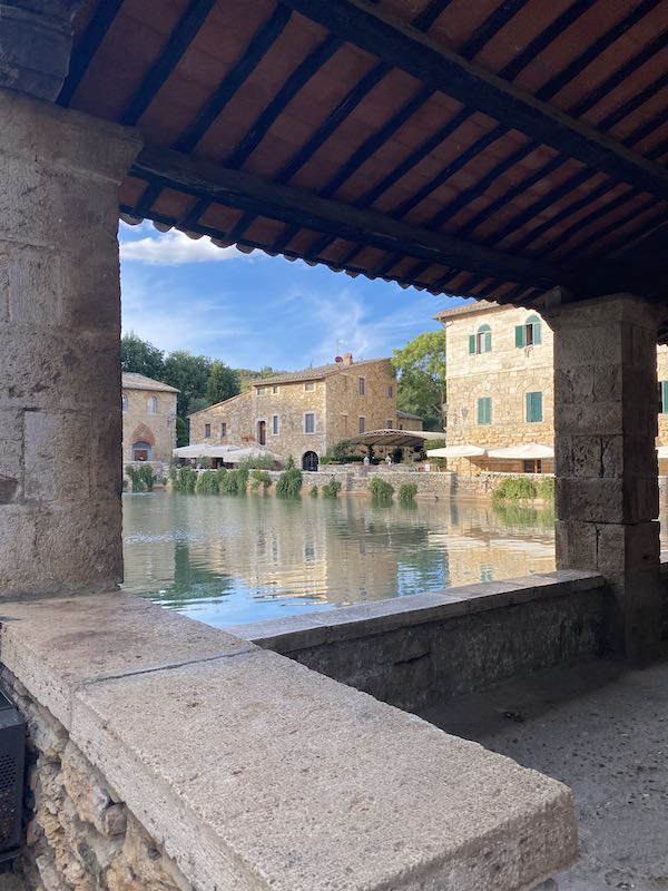 Bagno Vignoni main square from the loggia with buildings reflecting their image in water