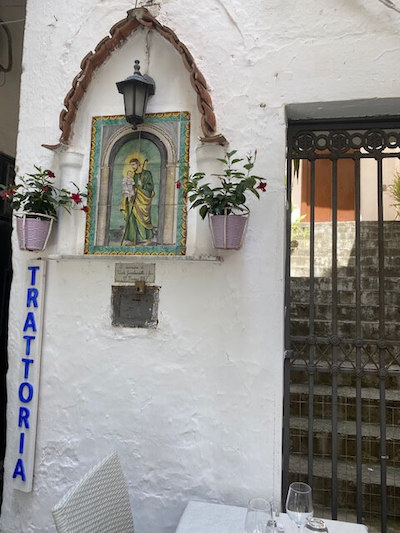 detail of religious image in Amalfi town, beside a restaurant sign