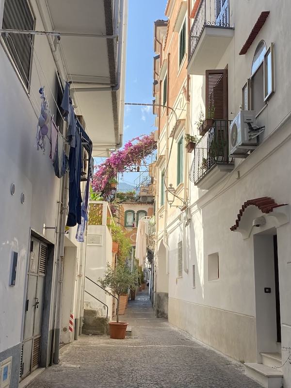 Car free alley in Minori, with white houses and pink flowers