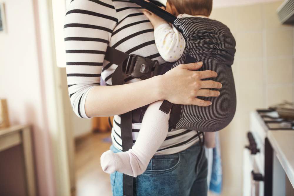 mom with baby in carrier in home kitchen