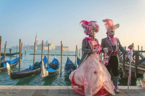 man and woman in traditional Venice carnival masks with Venice city in the background