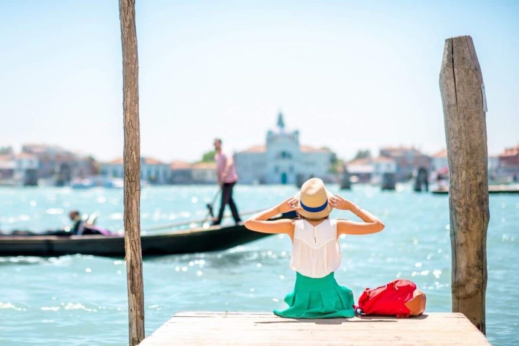 woman sitting on pier in venice in summer clothing