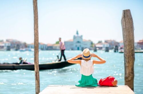 woman sitting on pier in venice in summer clothing