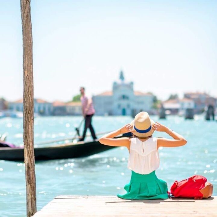 woman sitting on pier in venice in summer clothing