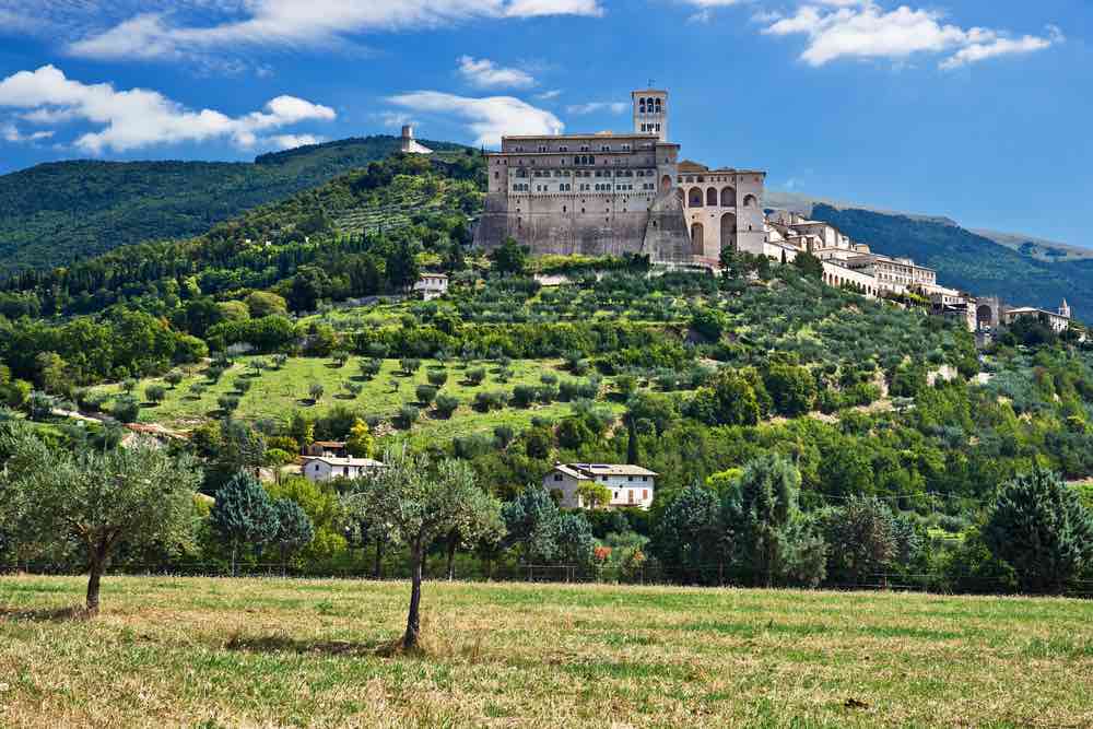 View of Assisi, Umbria, with green hills and trees in the foreground