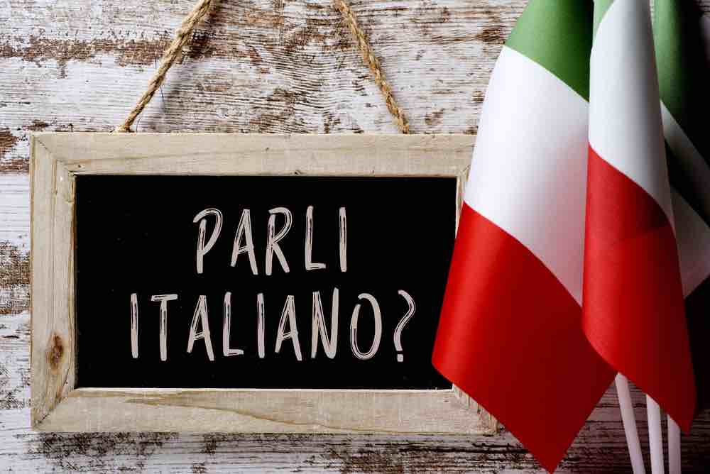 blackboard with sentence 'parli italiano' and Italian flag