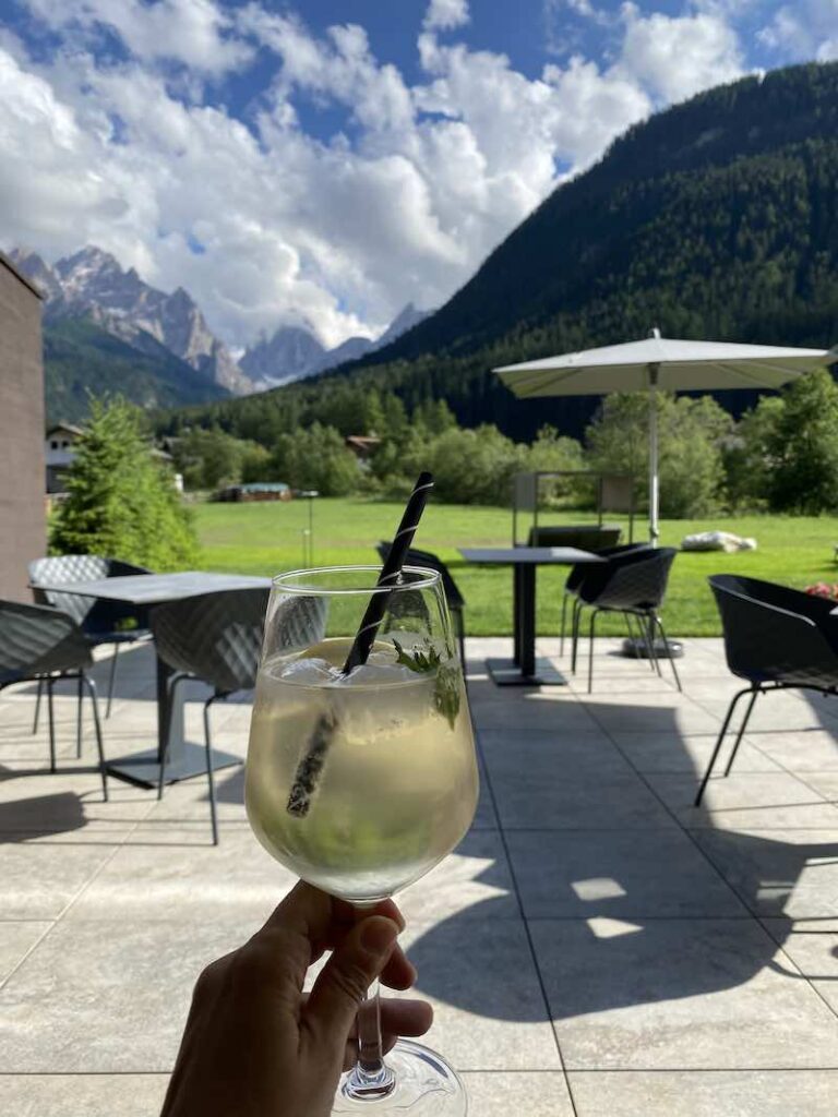 Glass of Hugo spritz with a background of the Dolomites, where the drink was born