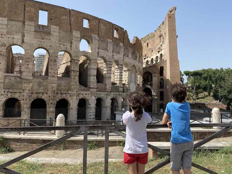 two children looking at the Colosseum in Rome from outside