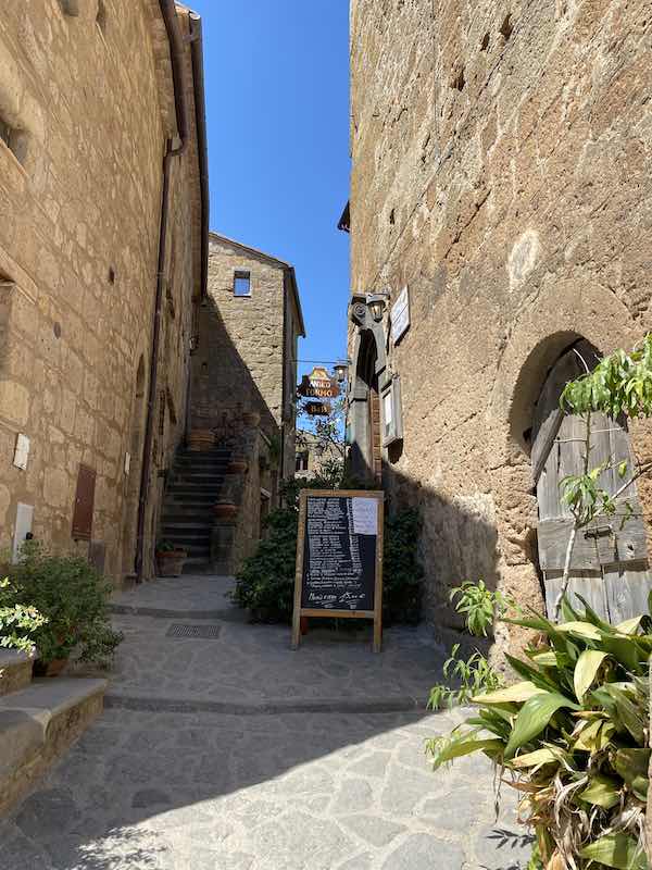 kleine straat in Civita di Bagnoregio met restaurant aan de rechterkant