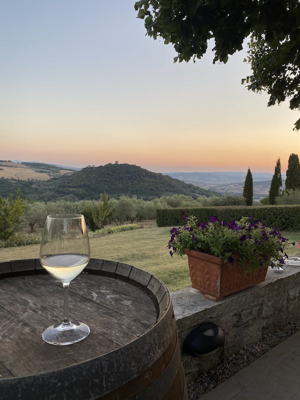 Glass of white wine over barrel in wine estate in Tuscany's Val D'orcia at sunset