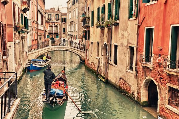 Gondola in Venice canal on winter day with gondolier wearing black jacket