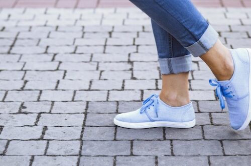 close up of woman feet wearing blue walking shoes on cobblestone