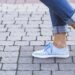 close up of woman feet wearing blue walking shoes on cobblestone