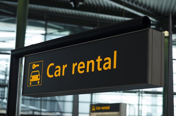 Car rental sign in airport, yellow text on black background and logo with car and key