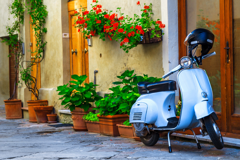 light blue vespa in historic town in Italy