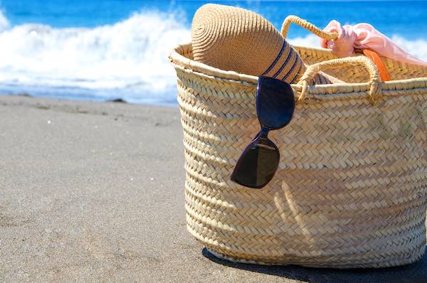 Beach bag on a beach with sun hat , sunglasses and other