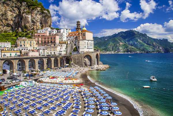 Amalfi Coast beach with beach clubs with blue umbrellas