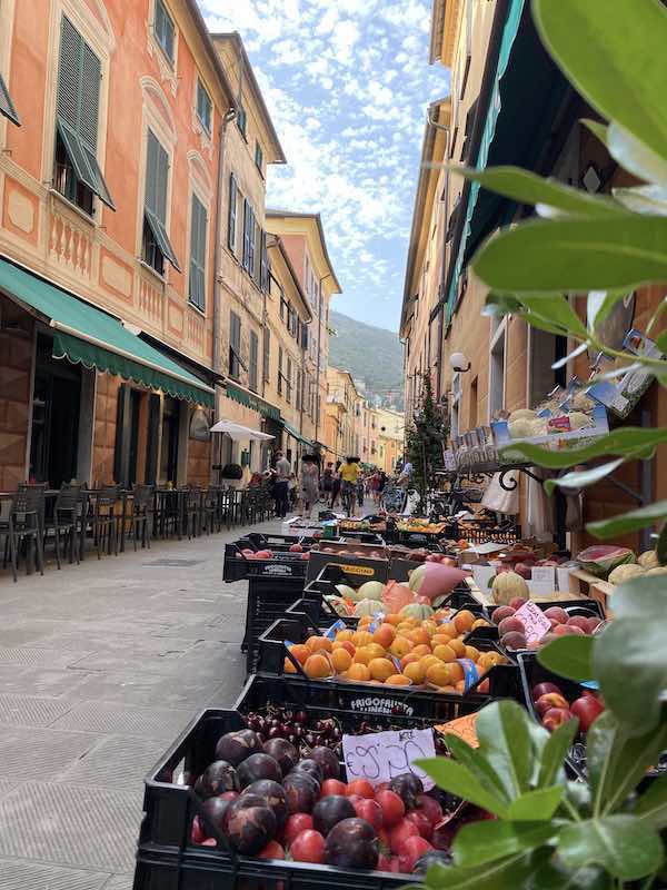 Main street in Levanto town center with a shop selling fresh fruit in the foreground