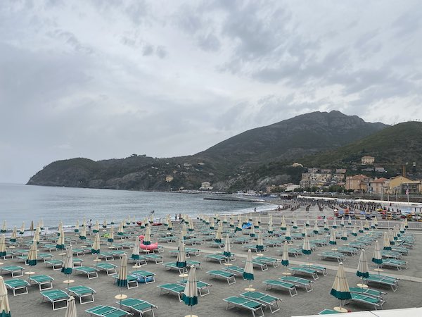 Beach of Levanto with green sunbeds and closed umbrellas on an overcast day