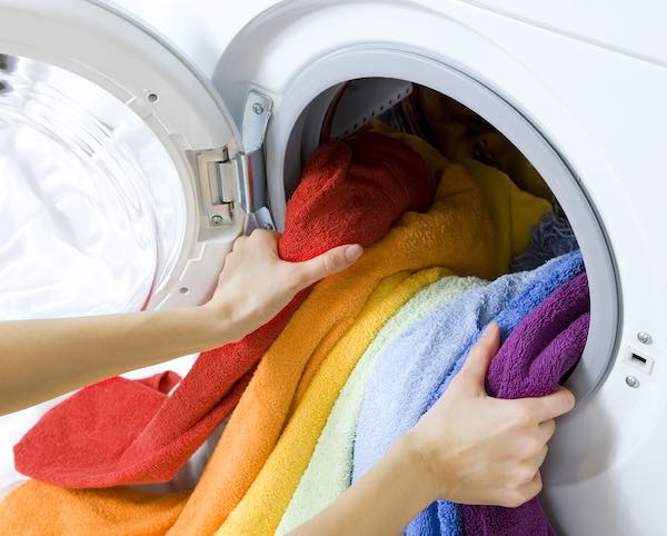 woman hands taking out of washing machine a colorful load of laundry