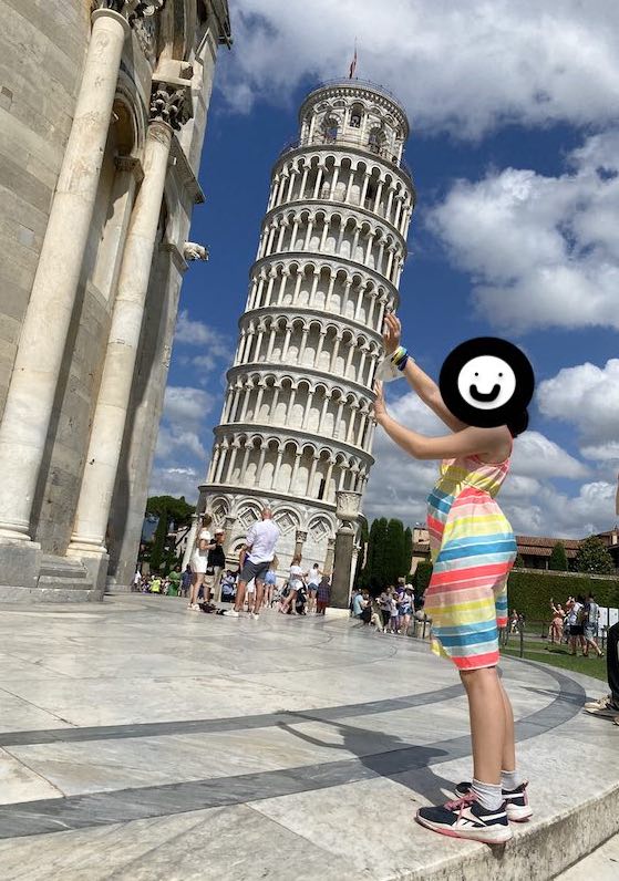 My daughter pretending to hold up the leaning tower of Pisa