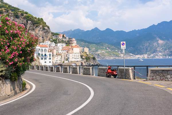Red scooter by the road on Amalfi coast with Atrani town in the background
