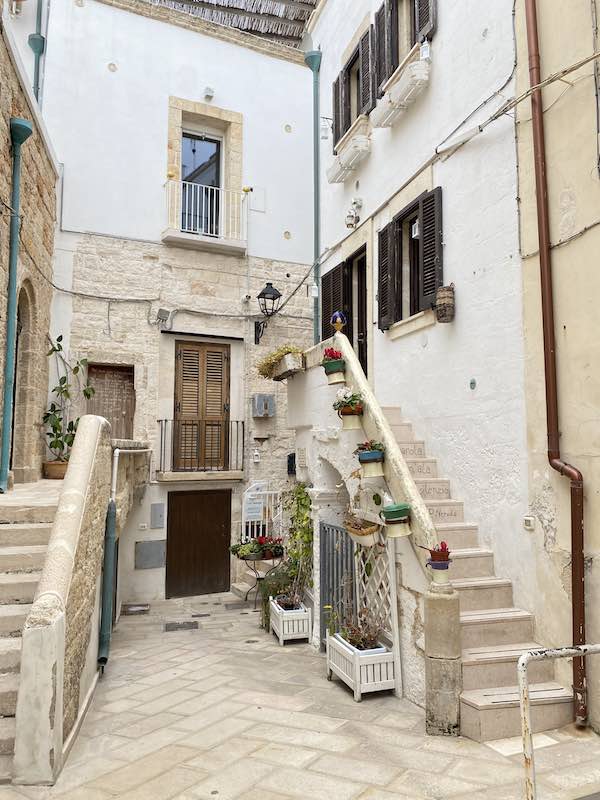 Cute whitewashed corner in Polignano al mare with steps and vases 