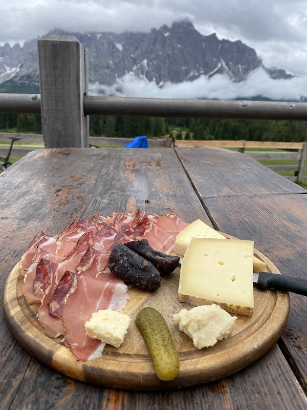 Dolomites food: charcuterie board with mountains in the background