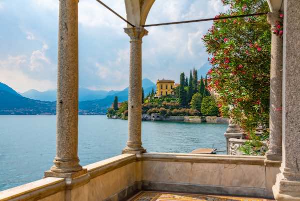 View of lake Como and a beautiful yellow villa though architectural columns overlooking the lake
