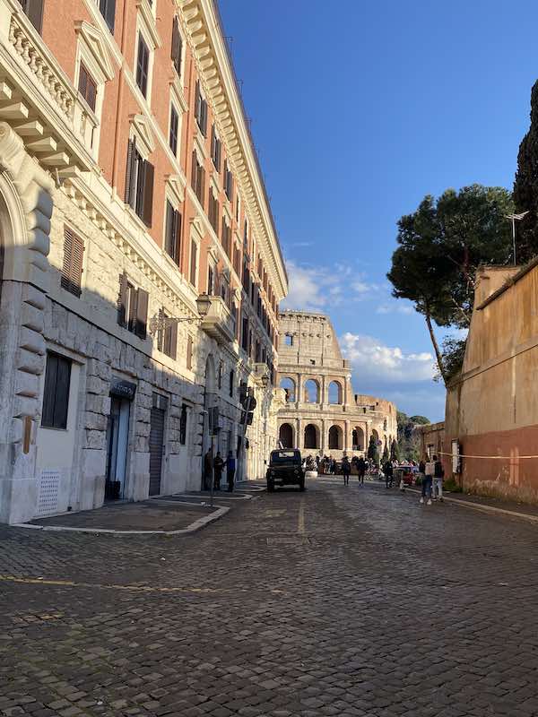 View of the Colosseum at the end of a cobbled street in Rome Rione Monti 