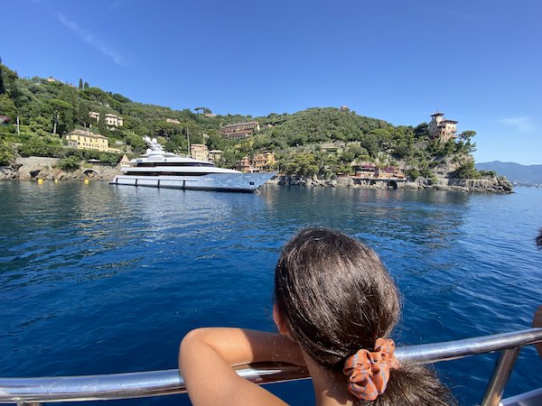 My daughter on the ferry going from Santa Margherita Ligure to Portofino, looking at a large yacht