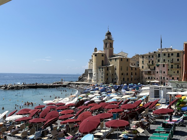 Camogli view in summer with dark red umbrellas on the beach